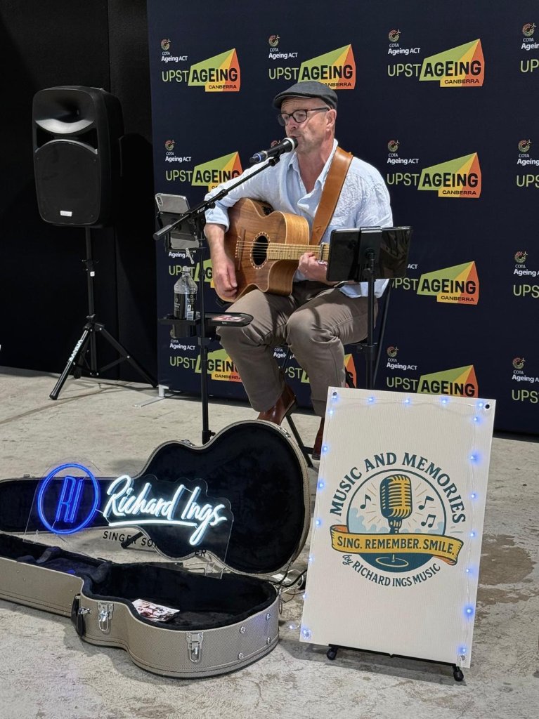 Richard Ings performing at UpstAgeing Canberra with Music and Memories signage