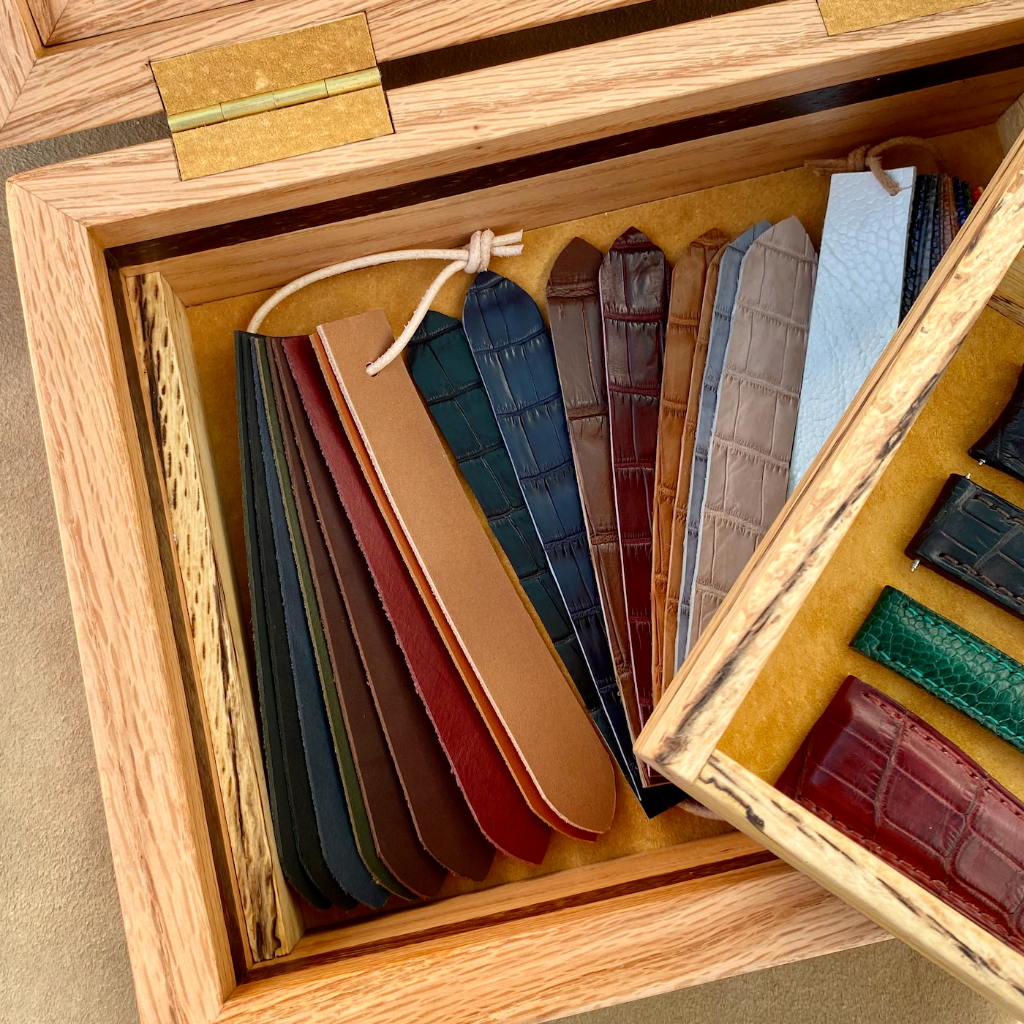 A wooden presentation box of leather strap swatches — crocodile, ostrich, calf and exotic leathers in a range of colours that Jacques brings to in-person consultations