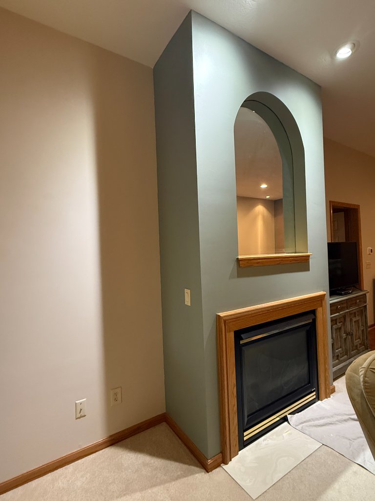 Living room fireplace wall painted in muted sage green