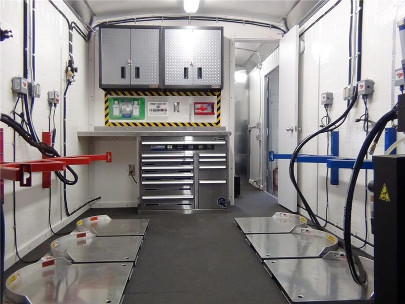 Interior of a professional spray foam rig showing A-side and B-side drum positioning, heated hose routing, transfer pump setup, and material conditioning zone for temperature and pressure control