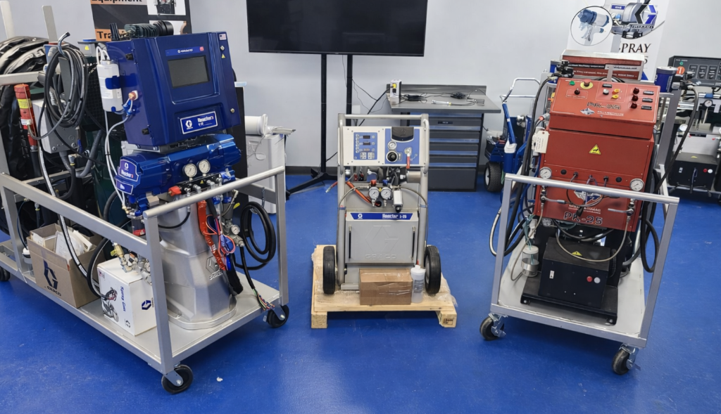 Multiple portable spray foam processing plant systems — Graco Reactor 3 E-30, Reactor E-20, and PMC PK-25 side by side in SprayWorks shop