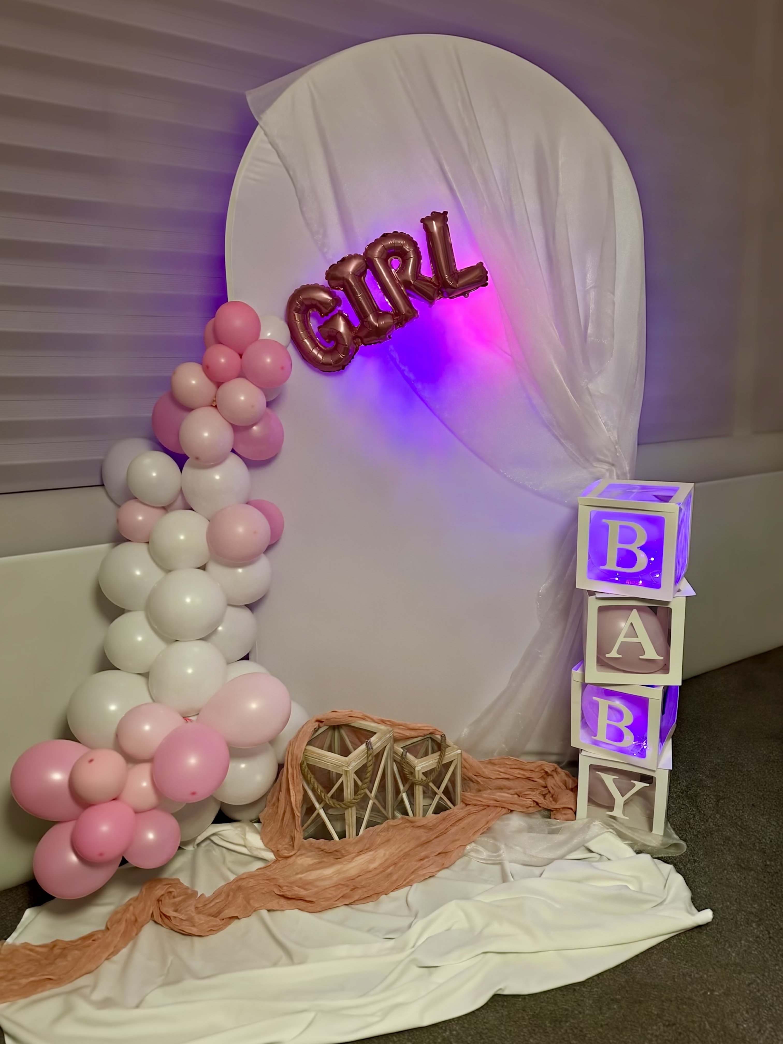 Baby girl event setup with pink and rose gold balloon garland and floral arch