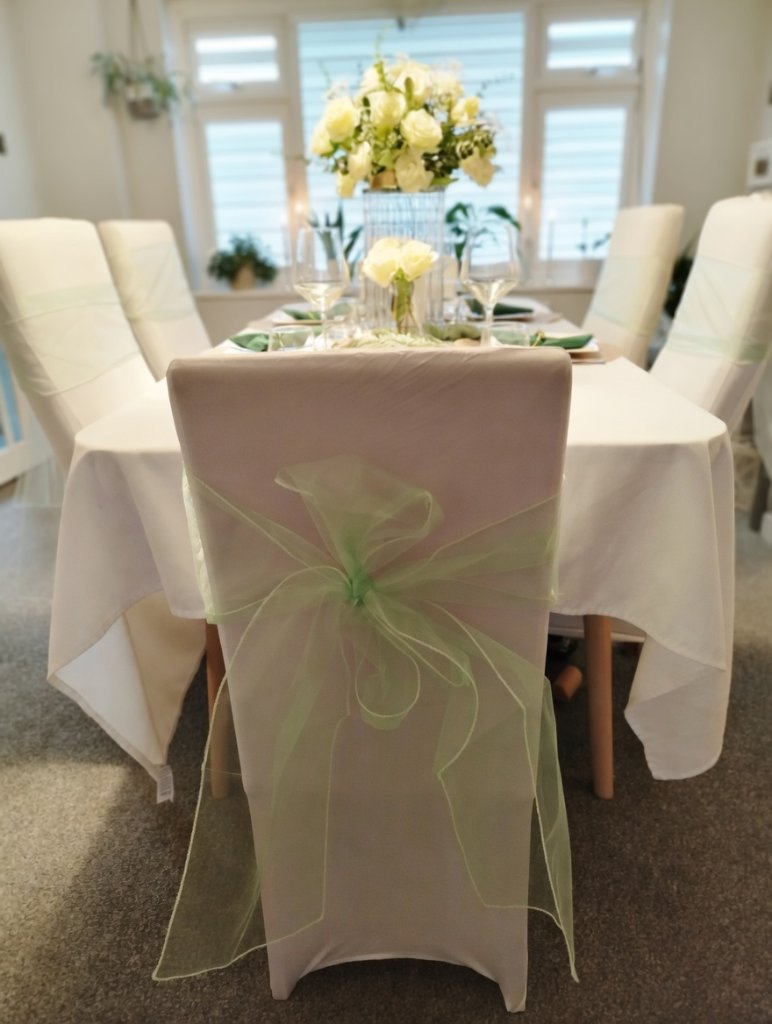 Green bow chair decoration with floral accents for a wedding ceremony
