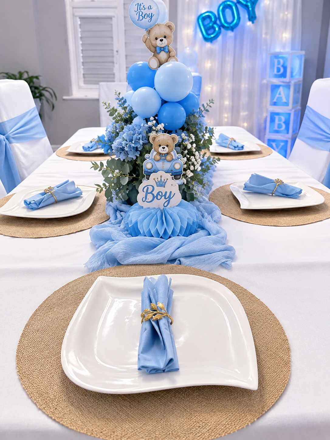 Blue baby boy themed dining table with teddy bear centrepieces, blue hydrangeas and gold napkin rings