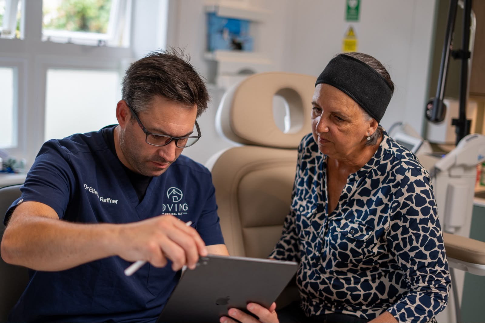 Dr Etienne Raffner reviewing a laser treatment plan with a patient during consultation
