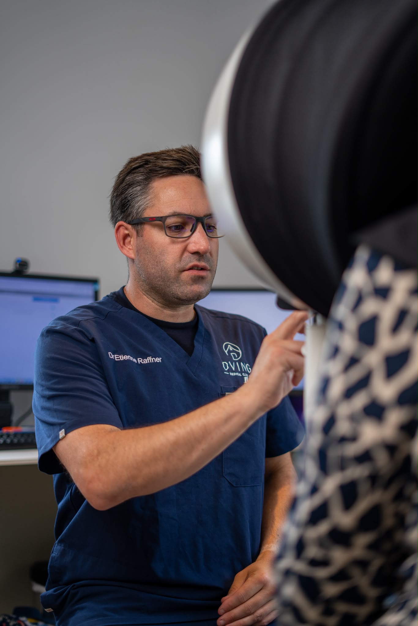 Dr Etienne Raffner performing a skin assessment with diagnostic equipment at Oving Medical Clinic