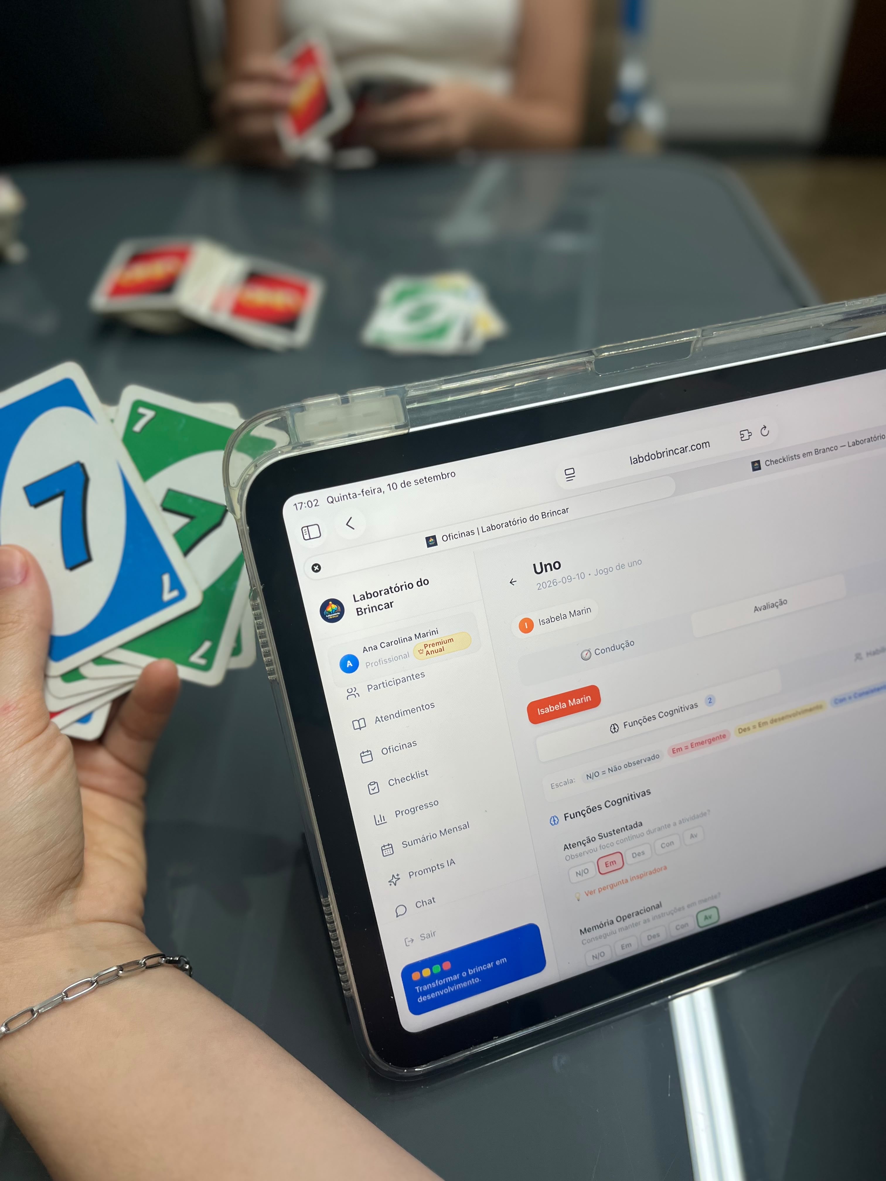 Profissional registrando comportamentos no checklist do Laboratório durante um jogo de cartas com a criança