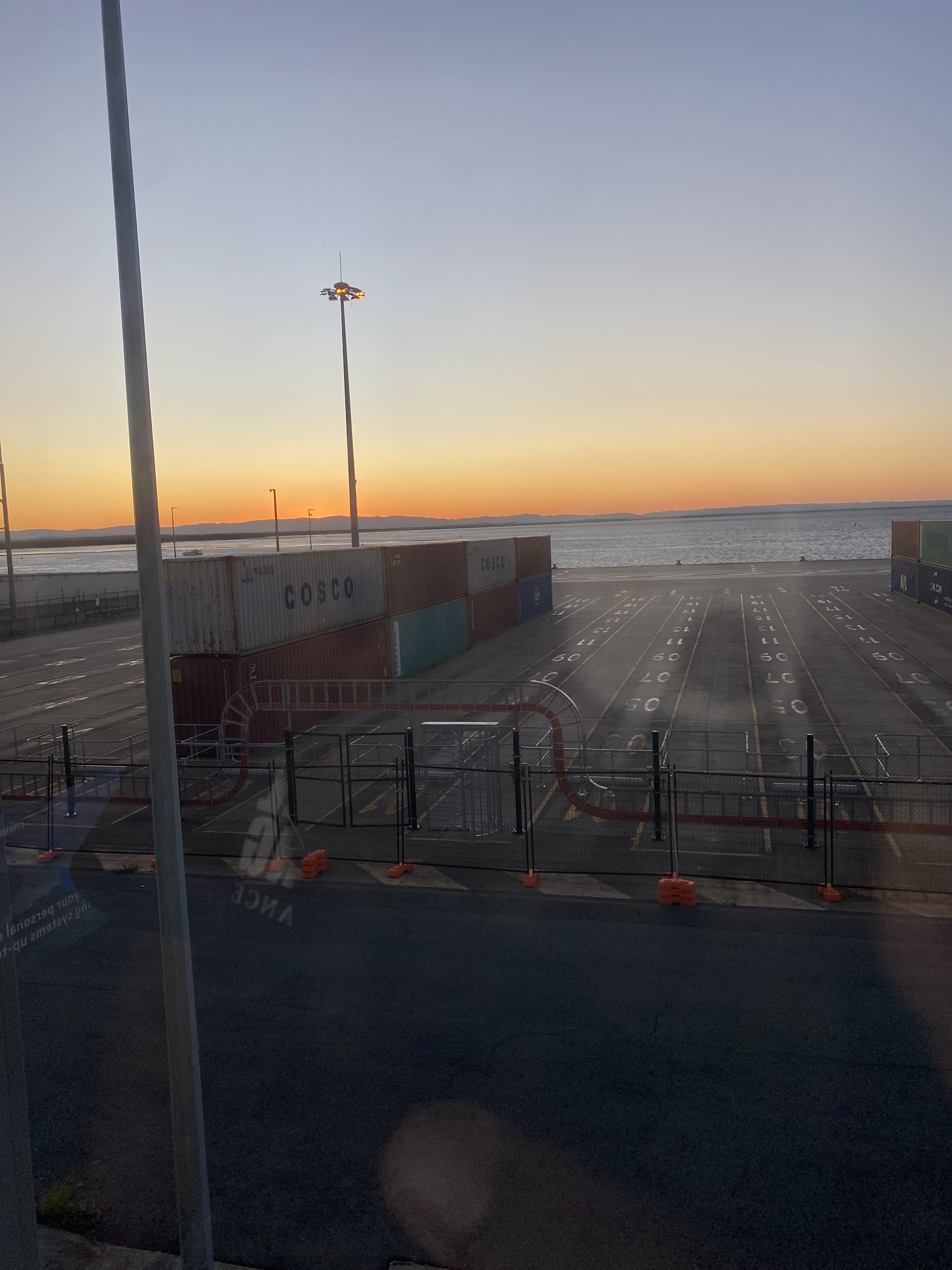 Container terminal, water and sunset horizon at dusk.