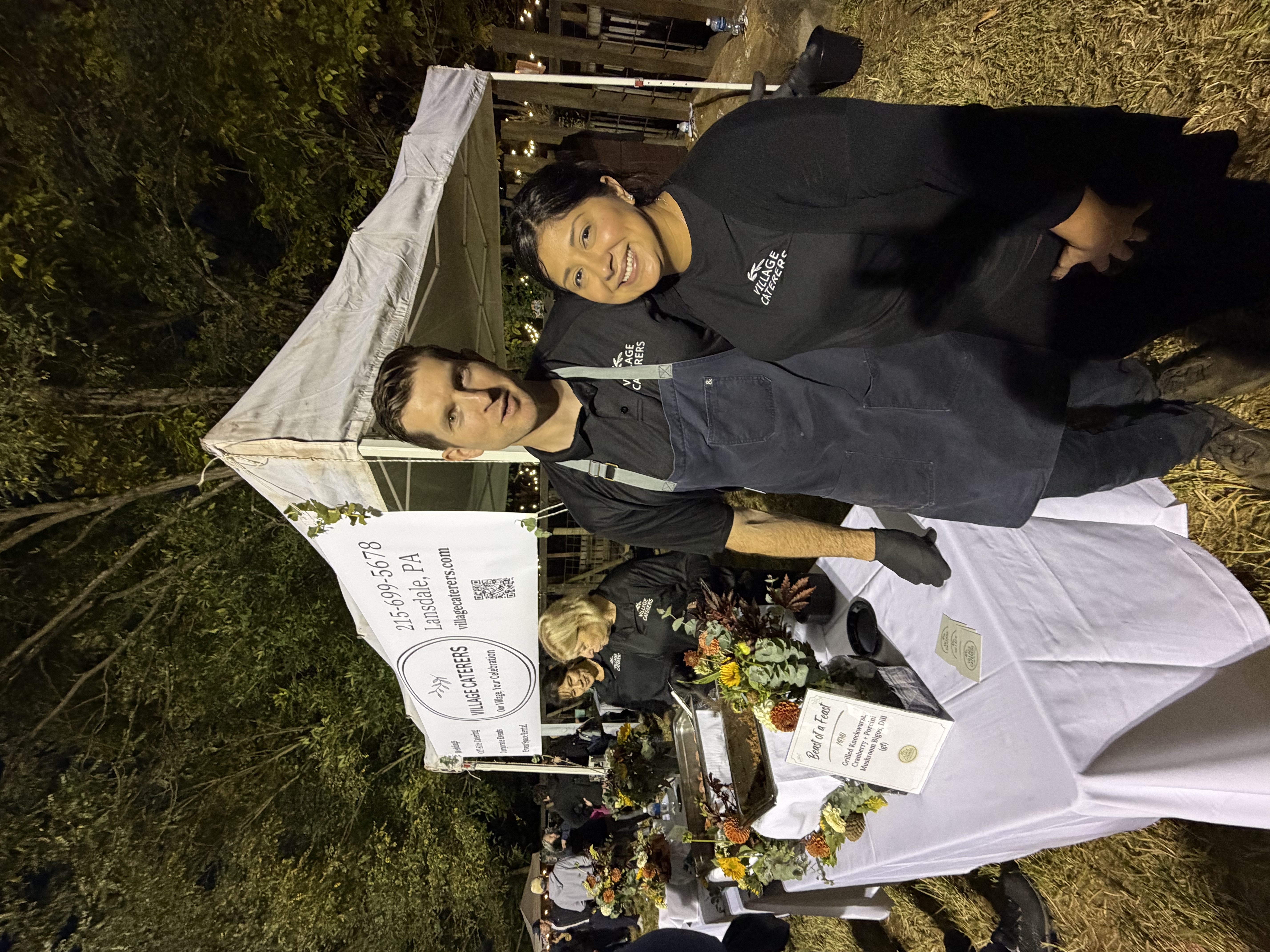 Andrew and Nicole Kedziora serving guests behind the Village Caterers tent at a community event