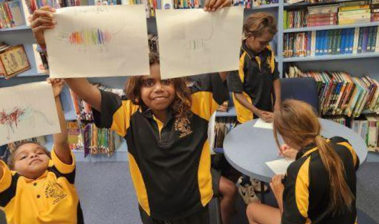 Students showing their drawings in a classroom