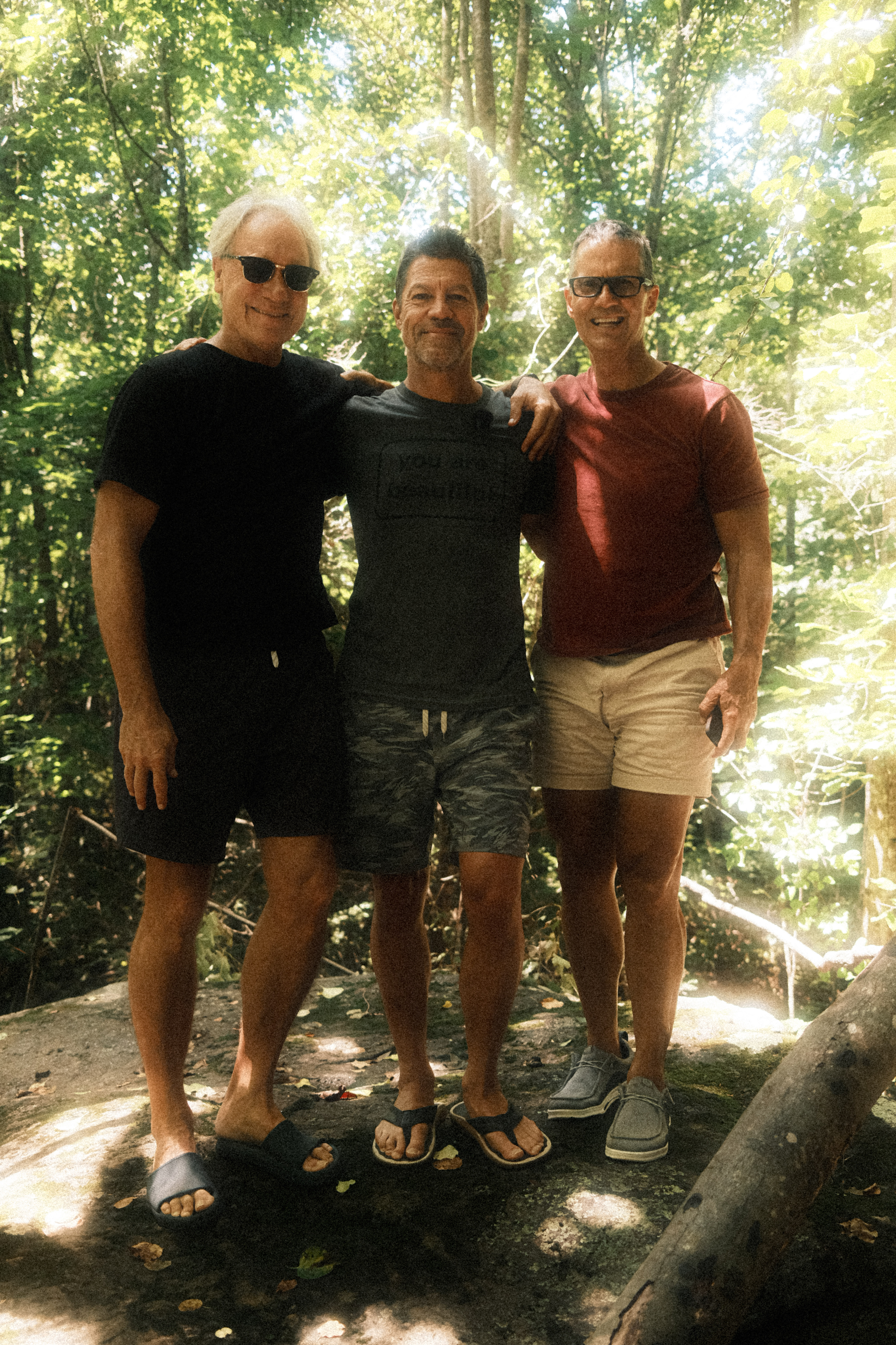 Three men with arms around each other on the rock