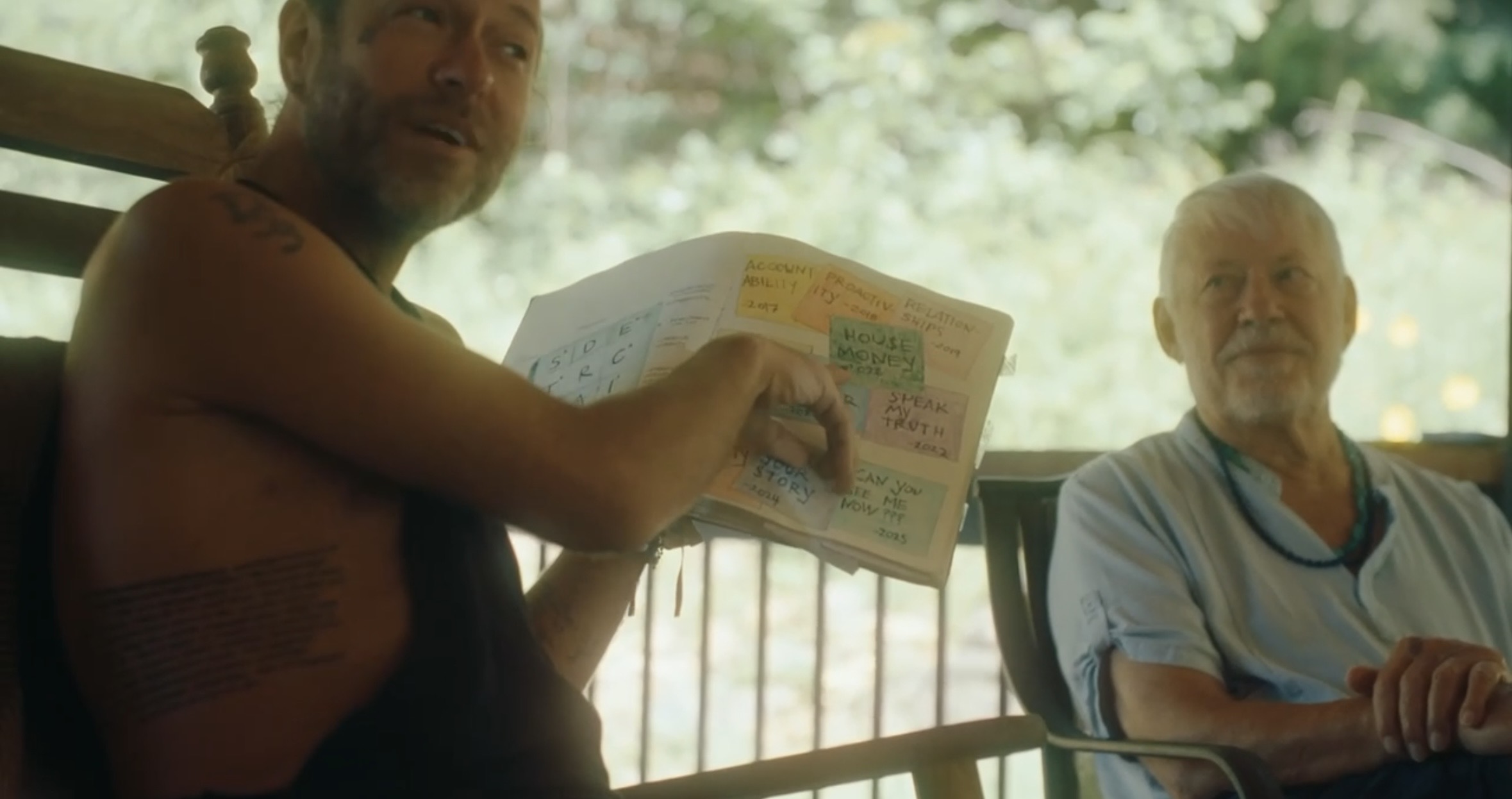 Two men on the porch with a journal of yearly intentions