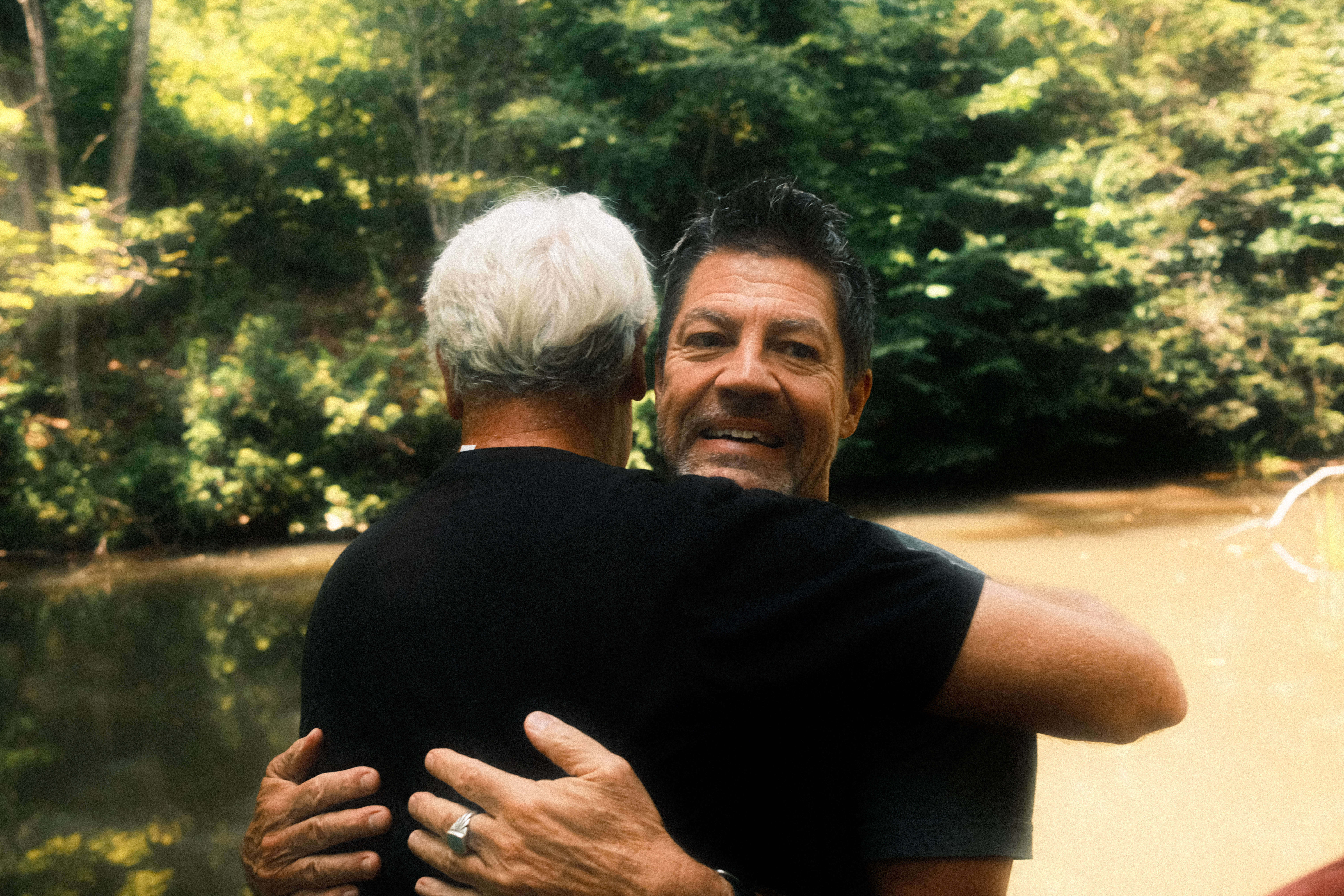 Two men embracing by the creek