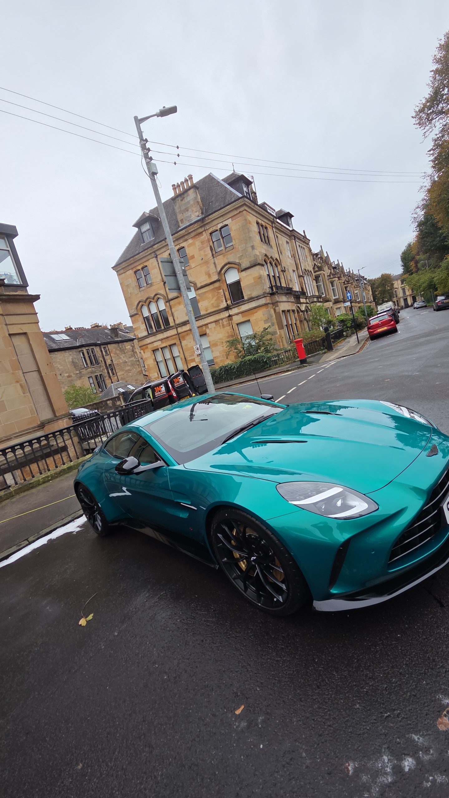 Teal Aston Martin detailed by JM Auto Care, detailing van in the background