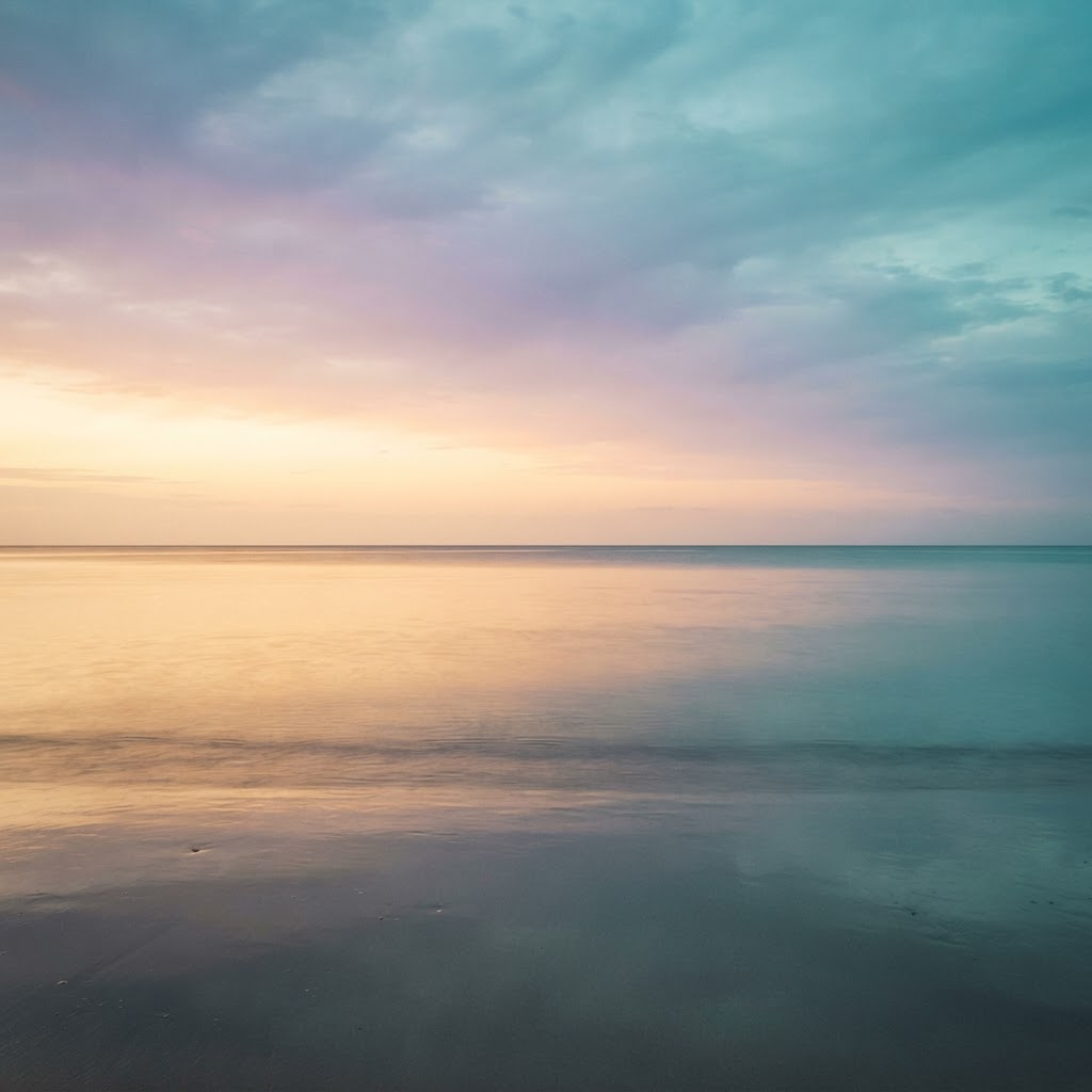 Calm horizon at twilight with a soft gradient from warm gold to cool teal, representing mood balance and stability