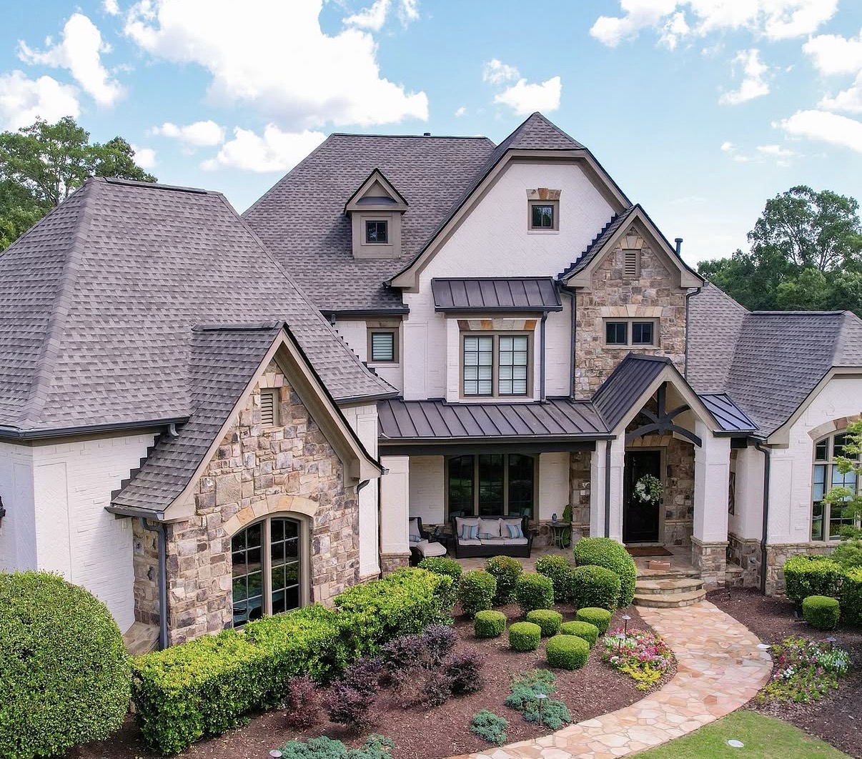Finished upscale home exterior with new architectural shingle roof and bronze standing seam metal accents