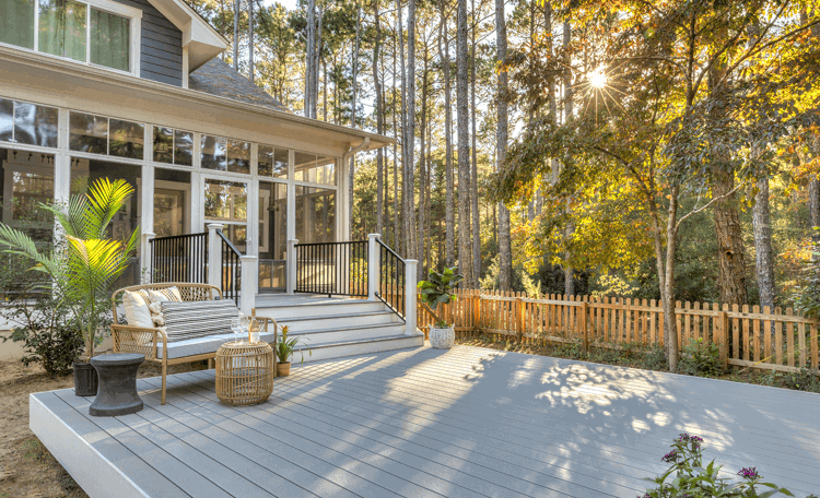 Completed residential composite wood deck with black metal balustrade railings overlooking wooded backyard