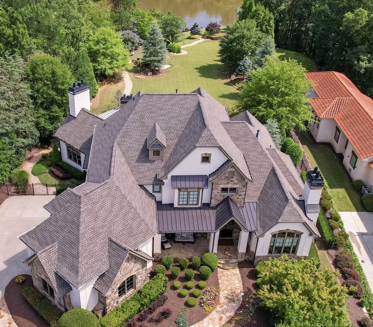 Aerial view of large multi-story home with complex roofline finished in architectural asphalt shingles and stone masonry exterior