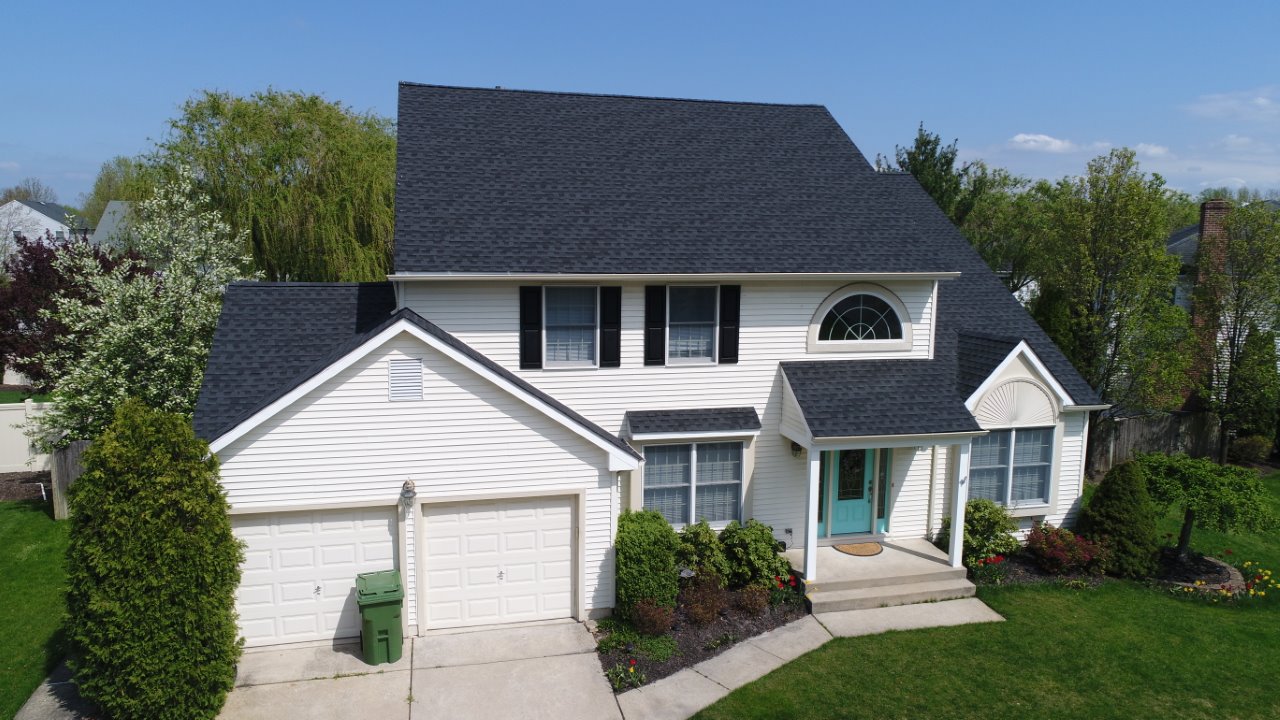 Two-story white siding home with charcoal-grey architectural shingle roof, turquoise front door, and covered entry porch