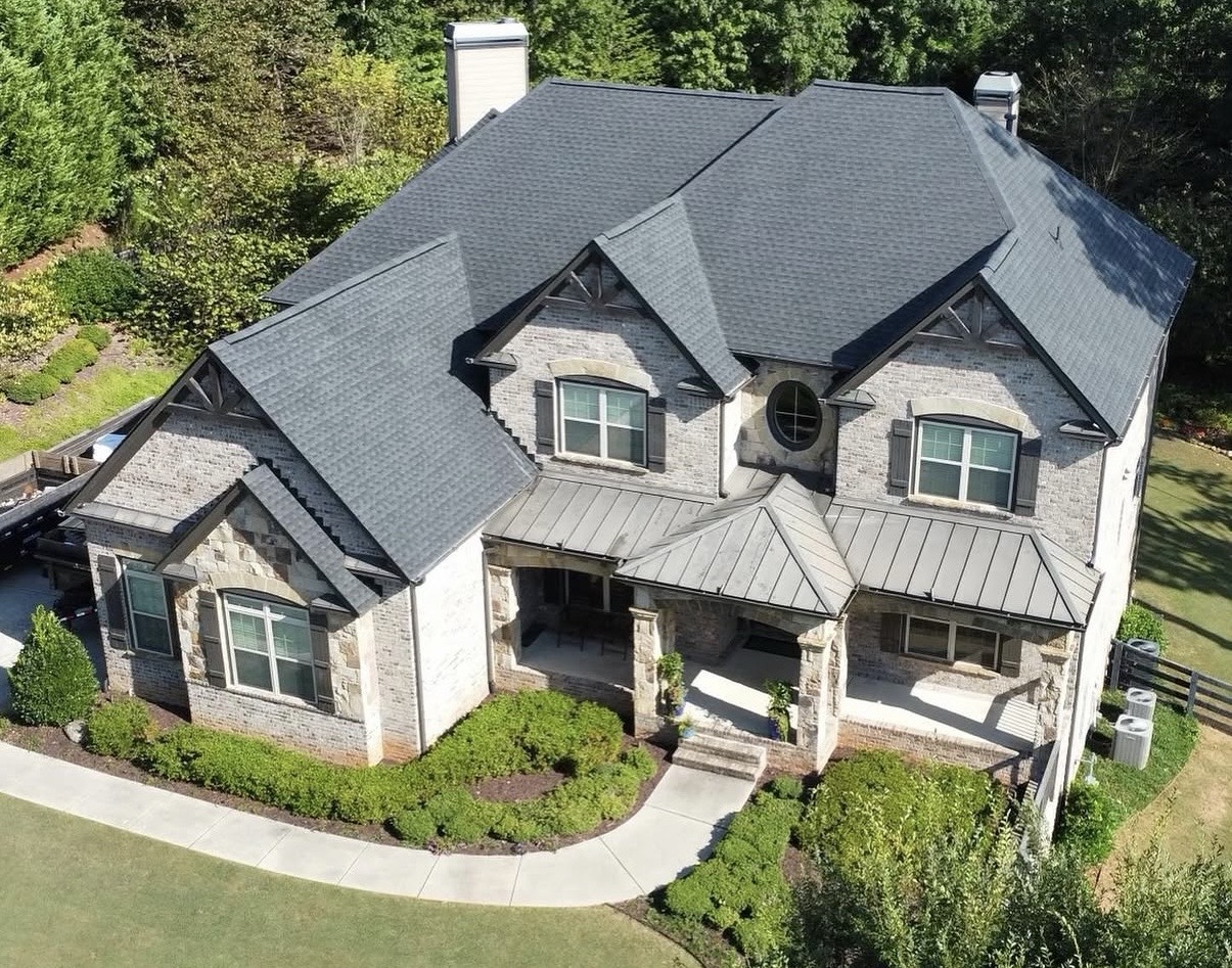 Aerial view of residential storm restoration project with dark charcoal shingle roof replacement and construction dumpster on site