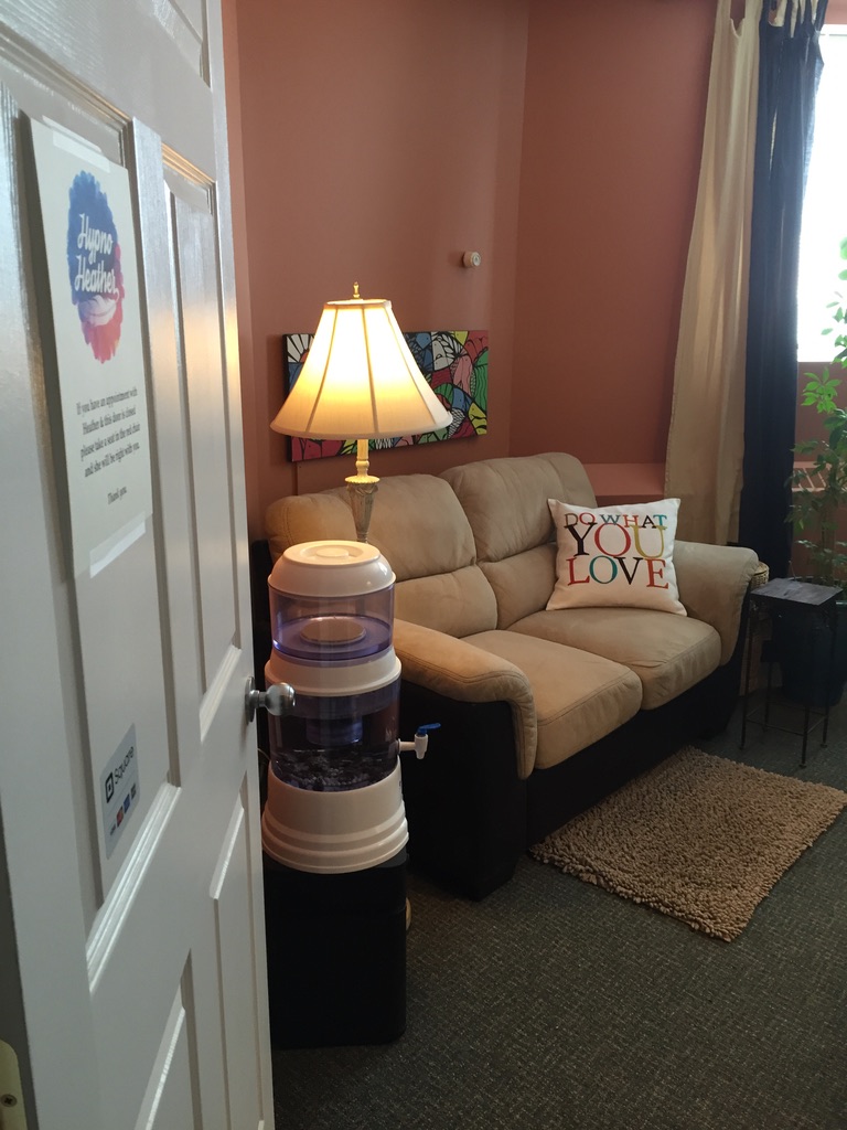 Client consultation space in Heather's Regina office with couch, lamp, and Do What You Love pillow