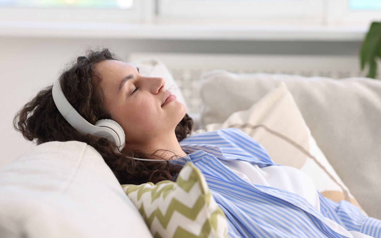 Client relaxing with headphones during an online hypnosis session from home.