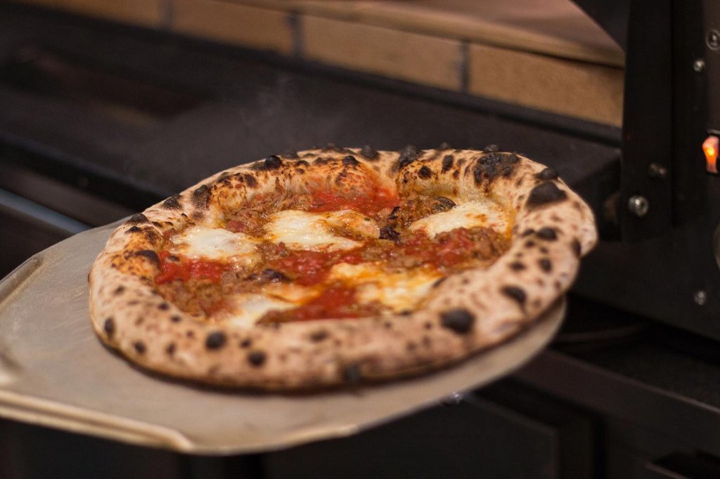 Pizza a cozer no forno a lenha
