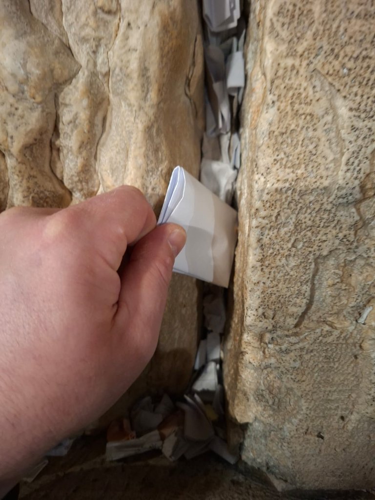 This is the moment the prayer begins to take effect — placed by hand into the ancient stones.