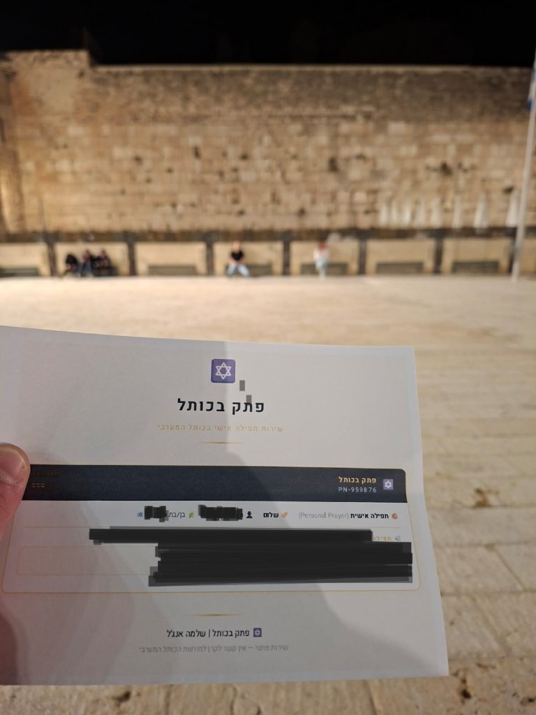 Holding your prayer note at the Western Wall — Jerusalem, by night.