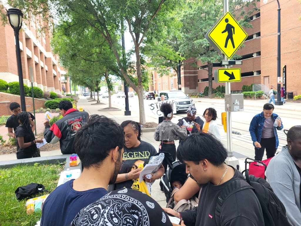 Organizers distribute flyers and talk with students on the sidewalk outside CPCC