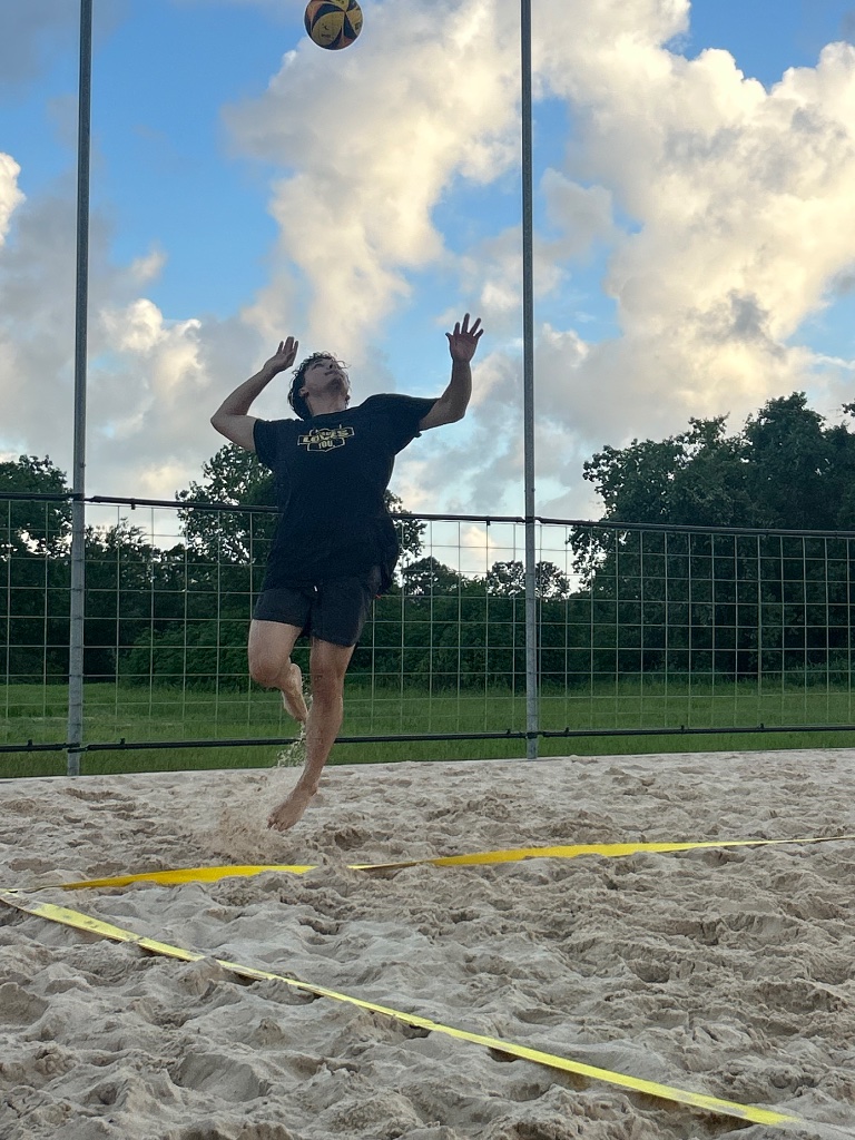 Player jump serving under cloudy skies