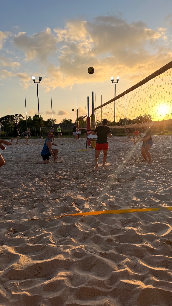 Sand volleyball action at sunset