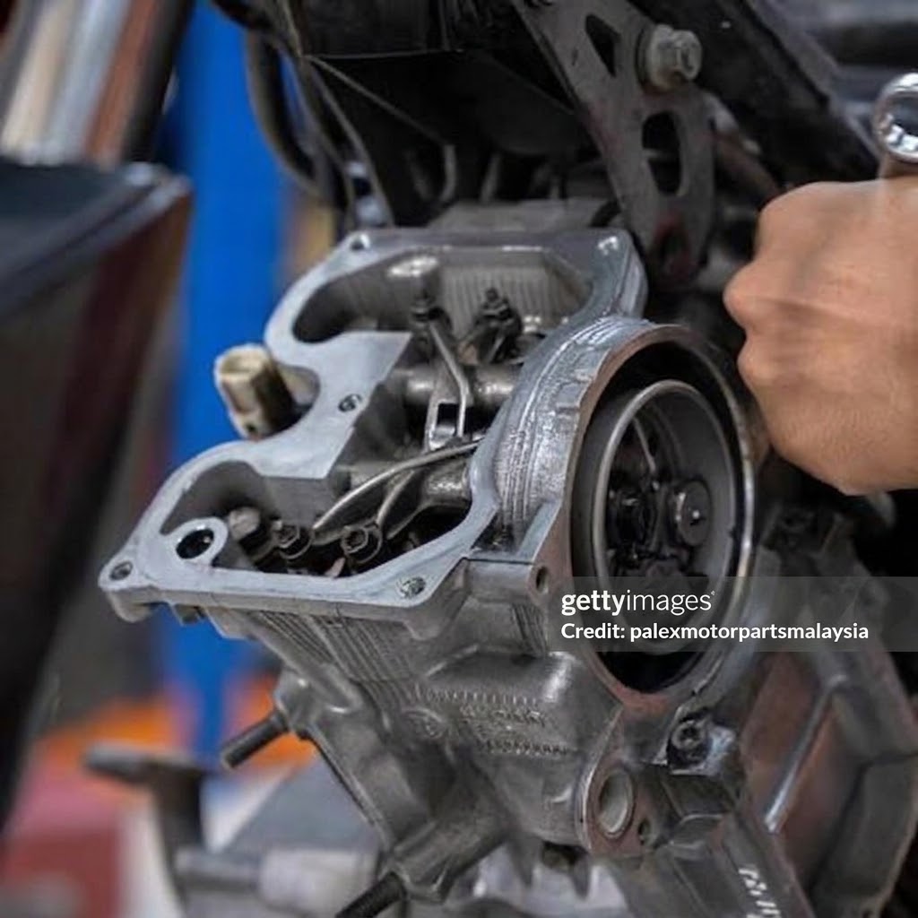 Mekanik melakukan kerja top overhaul pada cylinder head motosikal — komponen valve train, spring dan gasket top set dilihat secara terbuka