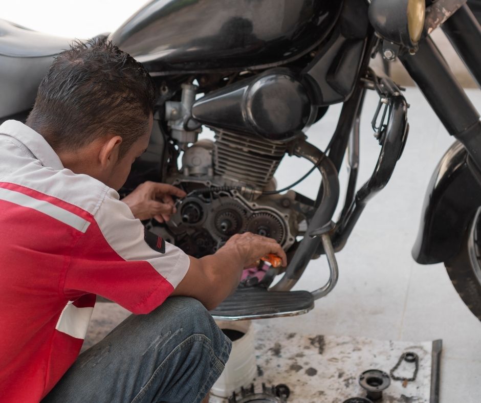 Mekanik memeriksa komponen dalaman enjin motosikal terpakai semasa ujian enjin sejuk