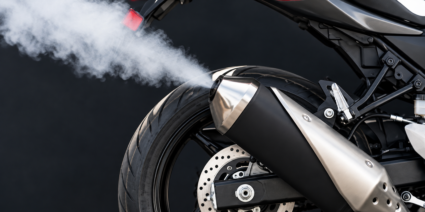Asap putih dan kelabu keluar dari ekzos motosikal menandakan minyak pelincir terbakar di kebuk pembakaran