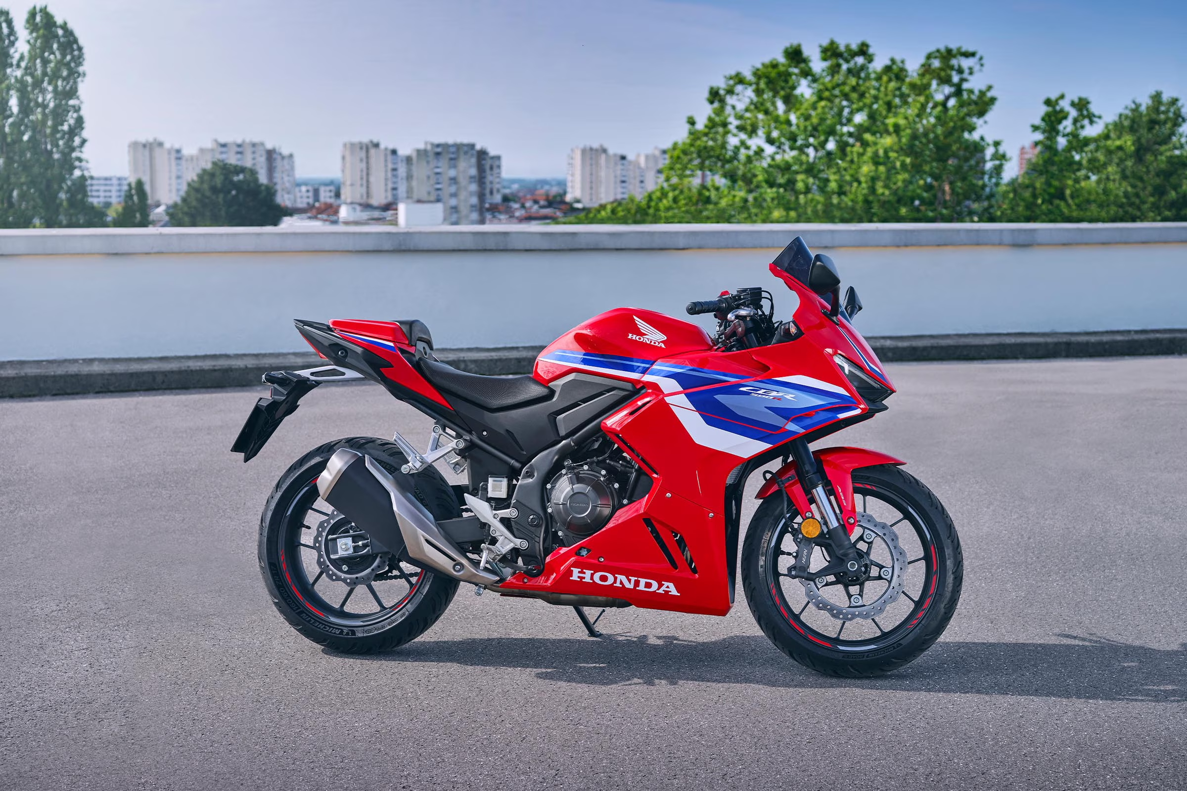 Pandangan sisi penuh Honda CBR500R merah dengan decal biru dan putih