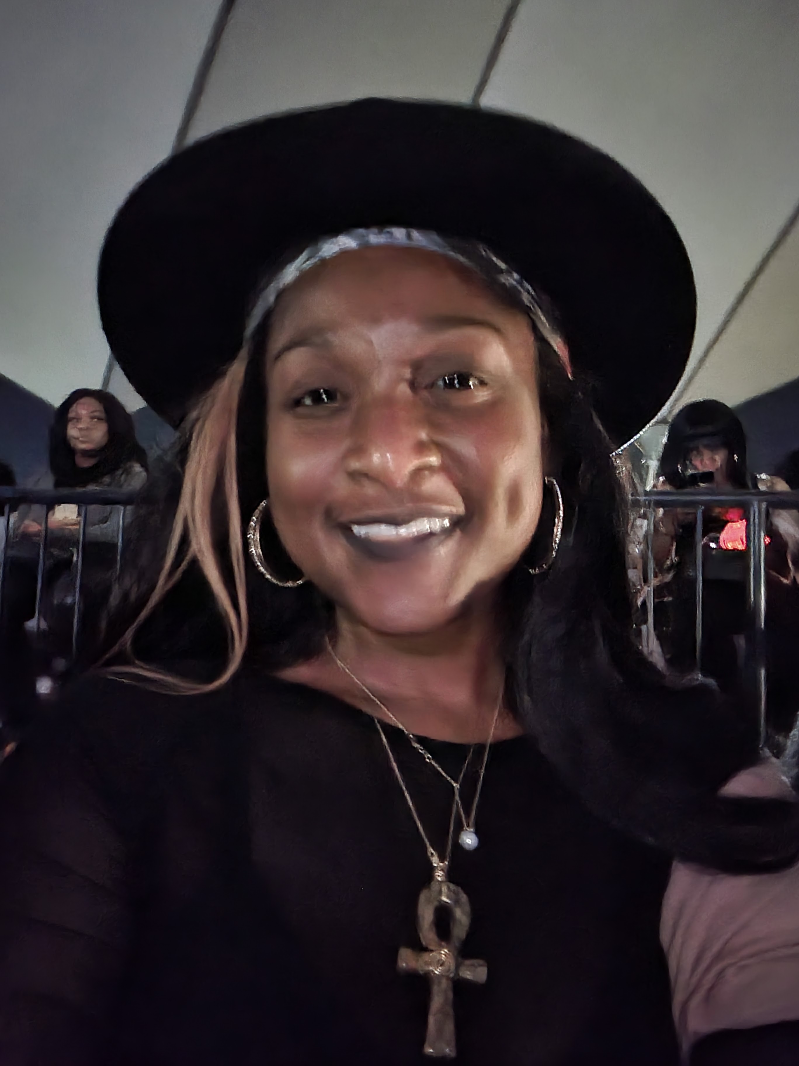 Queen Mercy wearing a black fedora and an Ankh pendant at a professional event