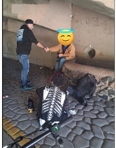 Volunteer shaking hands with a person during street outreach under an overpass