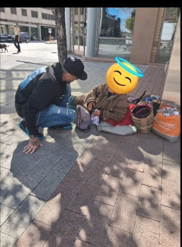 Volunteer kneeling on the sidewalk helping a person in need during street outreach