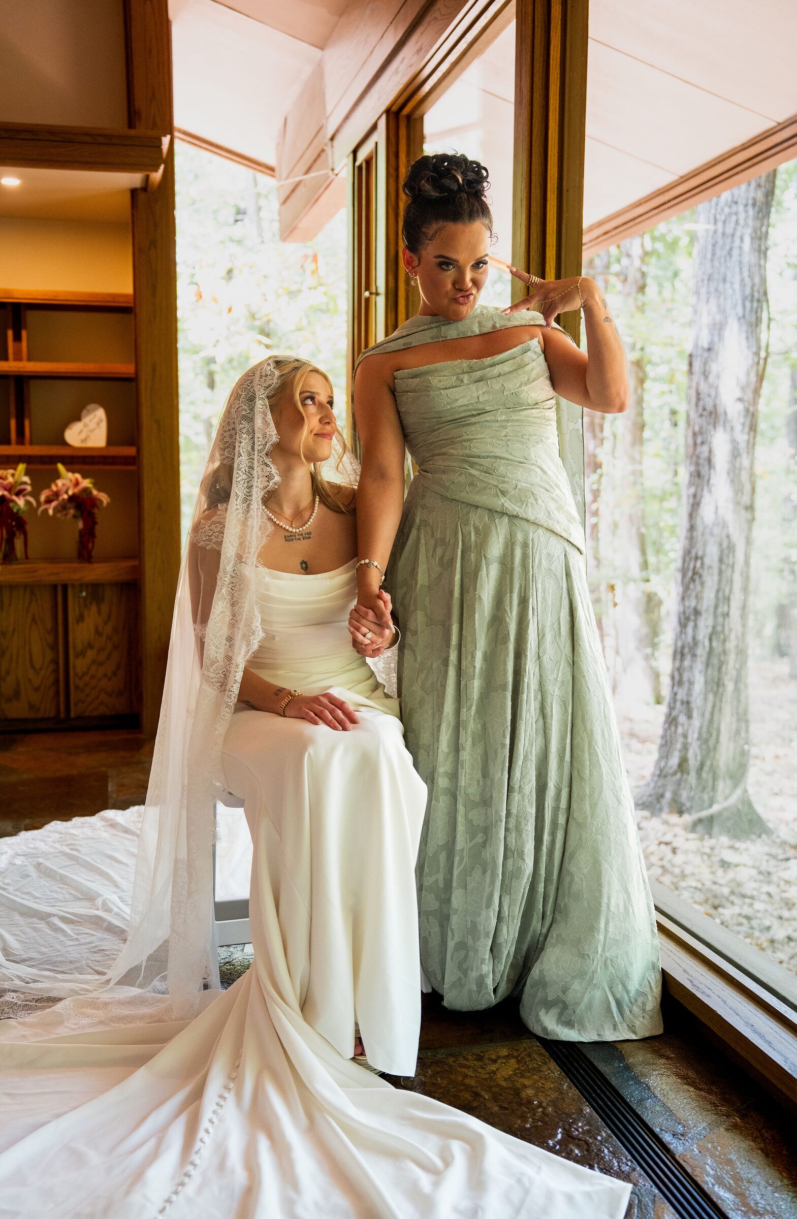 Bride in a white gown with a sage dressed bridesmaid inside the chapel at Garvan Woodland Gardens, Hot Springs, Arkansas
