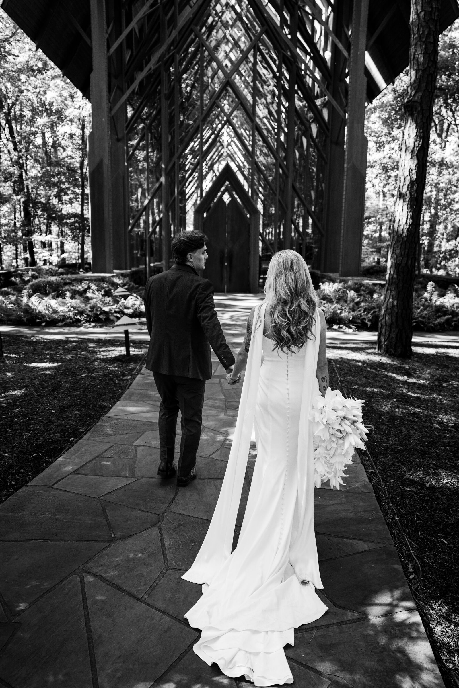 Black and white portrait of the couple walking toward the chapel at Garvan Woodland Gardens, Hot Springs, Arkansas