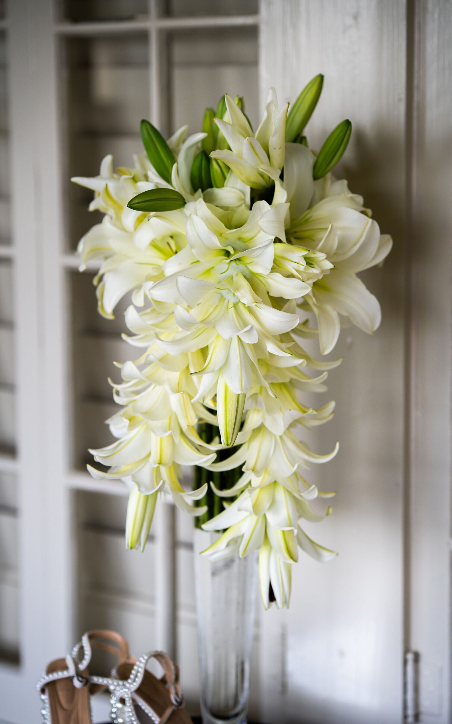 Cascading bouquet of white lilies with pearl bridal heels