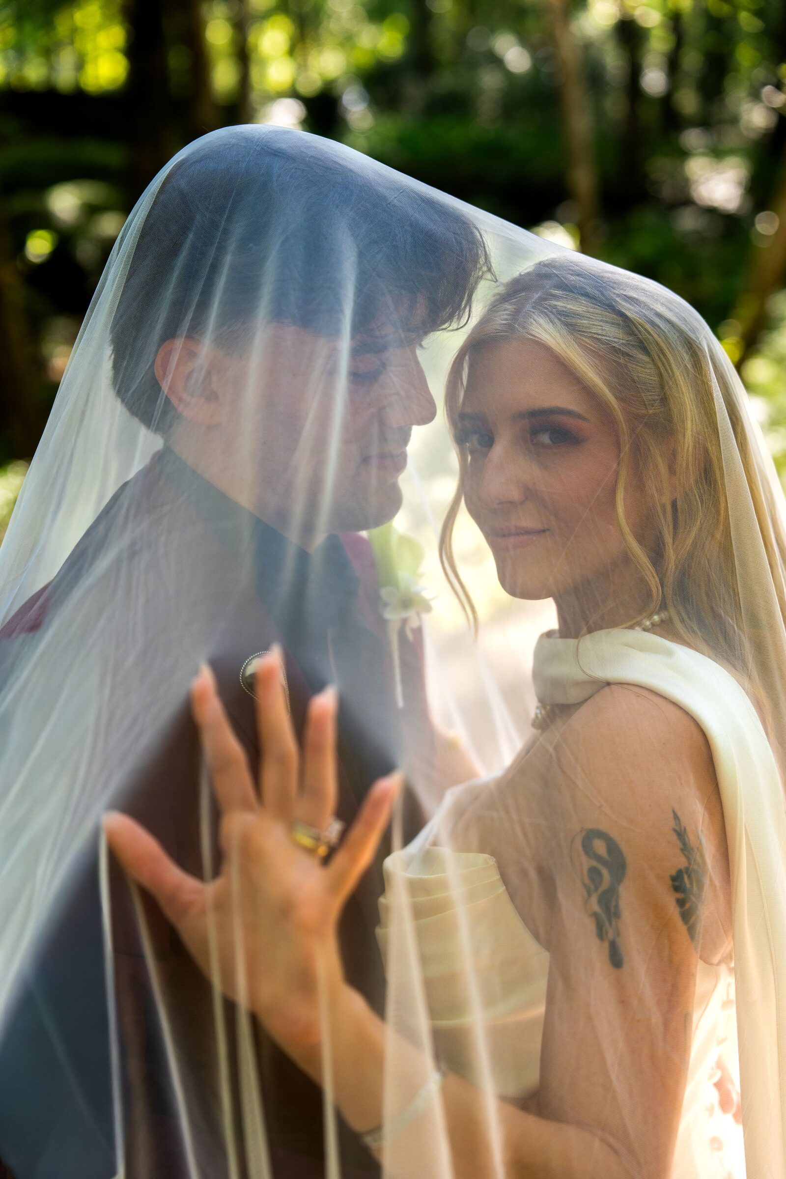 Couple beneath the veil with the bride showing her ring at Garvan Woodland Gardens, Hot Springs, Arkansas