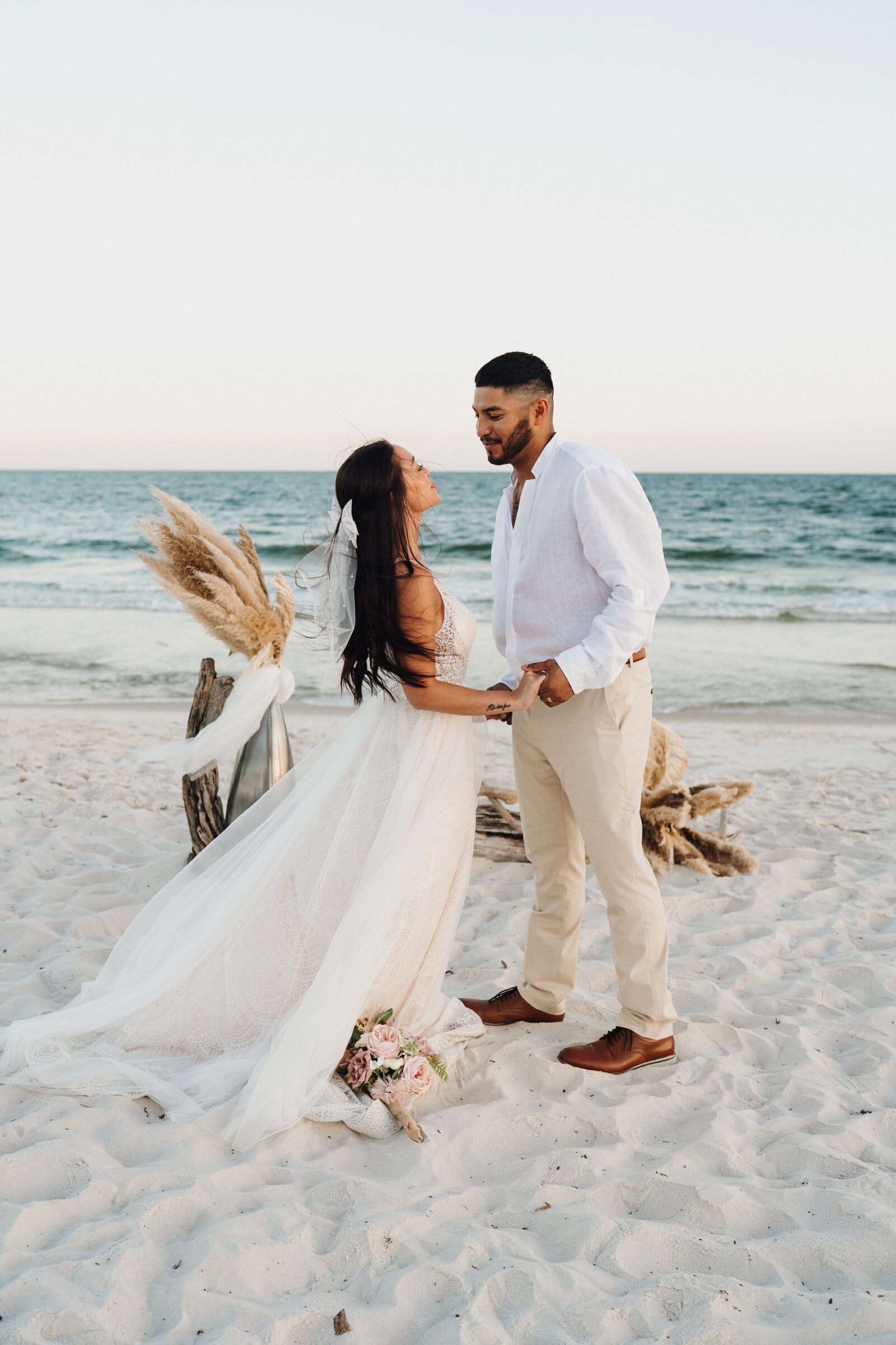 Couple standing on the sand at a sunset beach wedding ceremony
