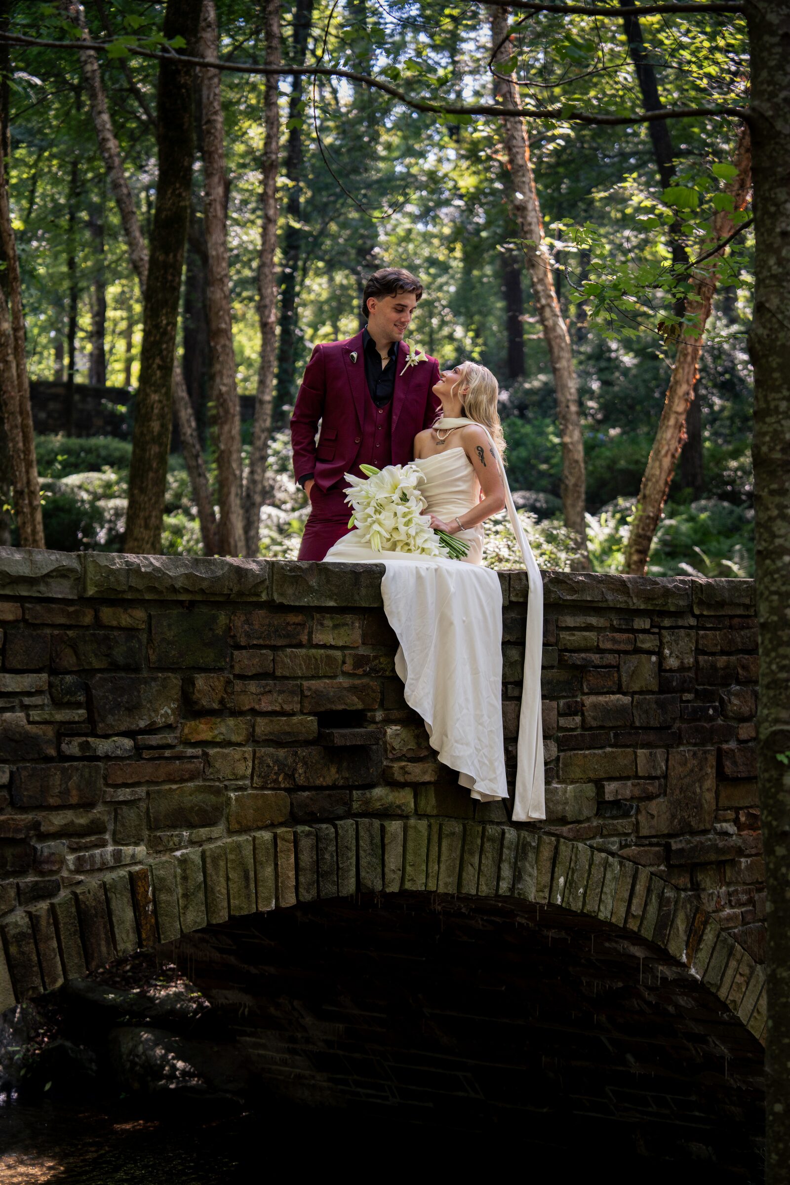 Bride and groom resting together on a stone bridge in the forest at Garvan Woodland Gardens, Hot Springs, Arkansas