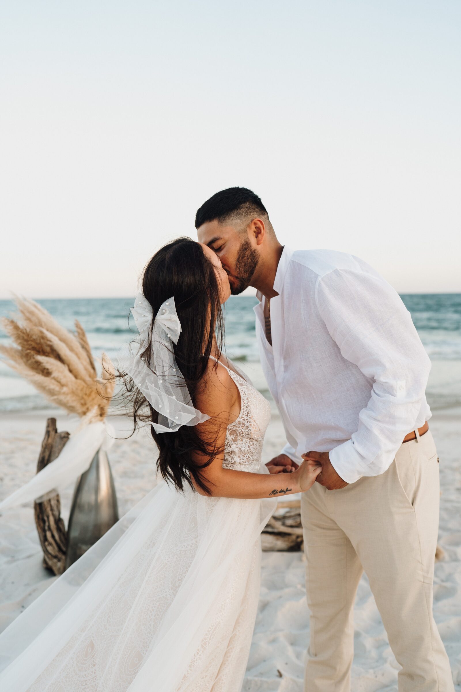 Couple kissing at a sunset beach wedding ceremony on the Gulf Coast