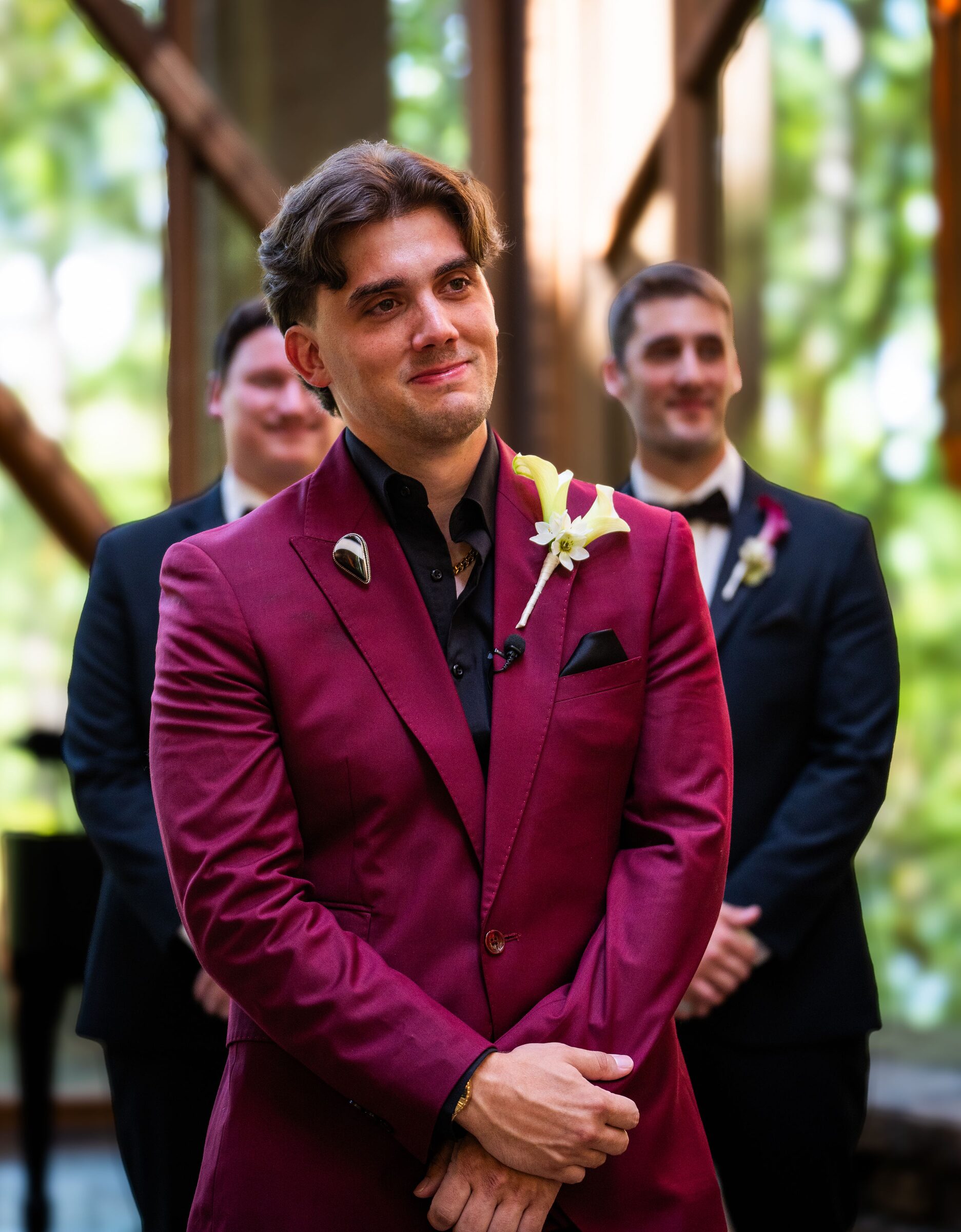 Groom in a burgundy suit with a lily boutonniere standing at the altar at Garvan Woodland Gardens, Hot Springs, Arkansas