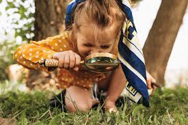 Young girl with magnifying glass exploring grass outdoors
