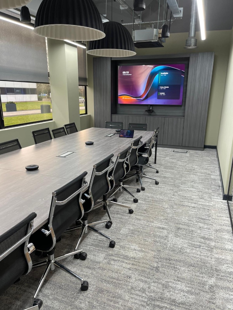 A commercial AV environment built by Pineapple AVI — a boardroom with screens active and a commissioned control system.