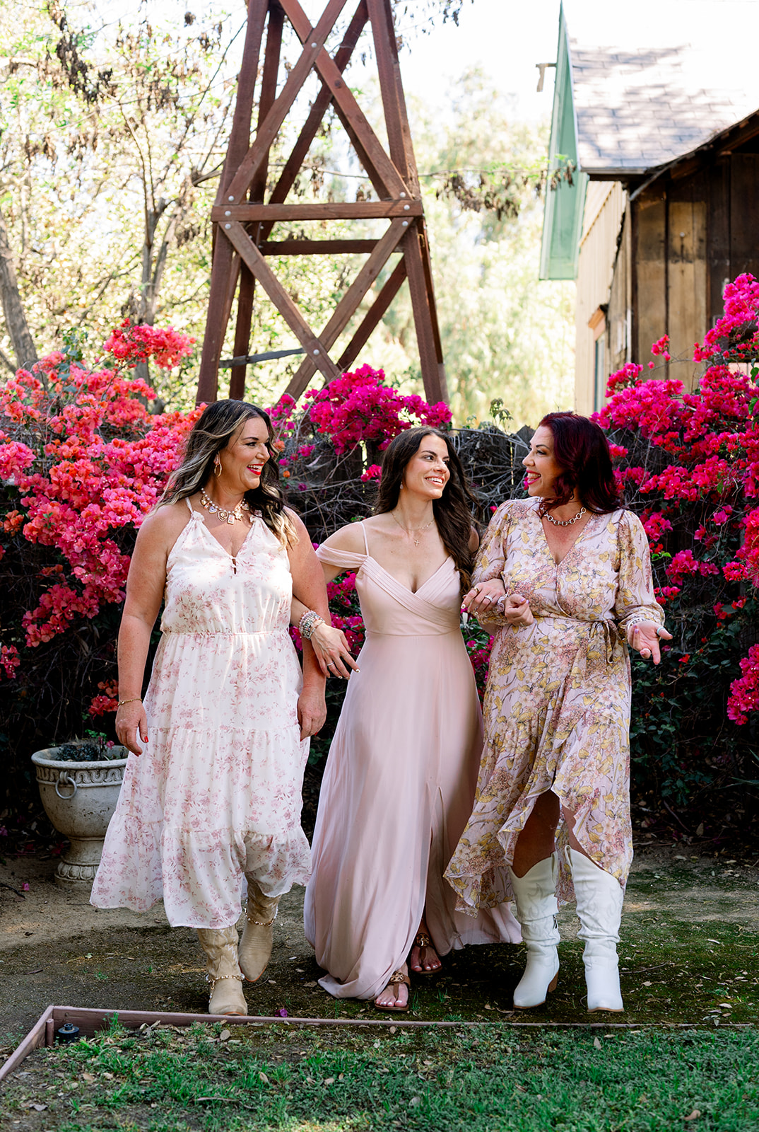 The three women of a content branding group walking together in a garden with a windmill